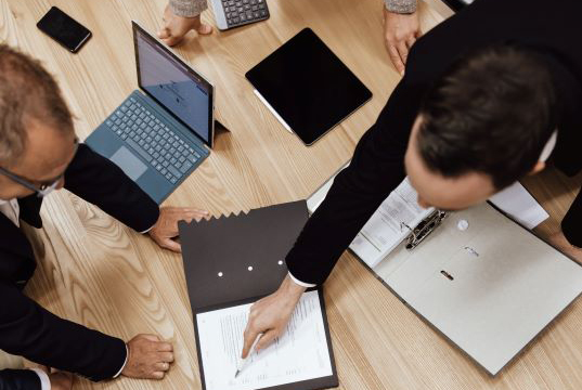 Männer mit Laptop und Ordner im Gespräch