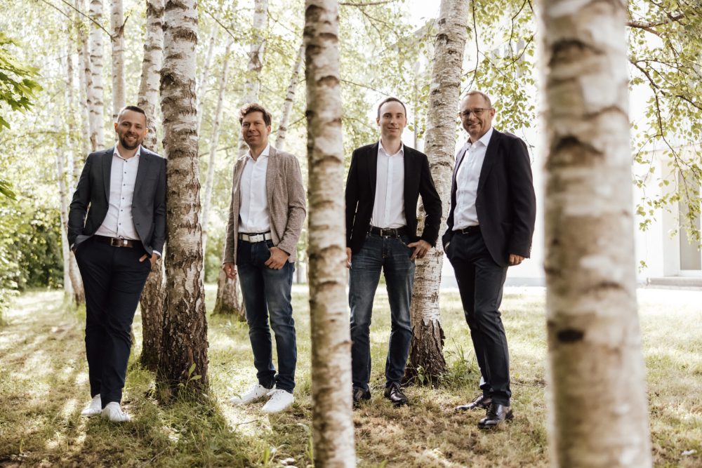 Vier Männer draußen mit Bäumen